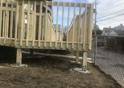 Newly constructed wooden deck with vertical railings and support posts, showcasing quality craftsmanship for outdoor living spaces and accessibility improvements.