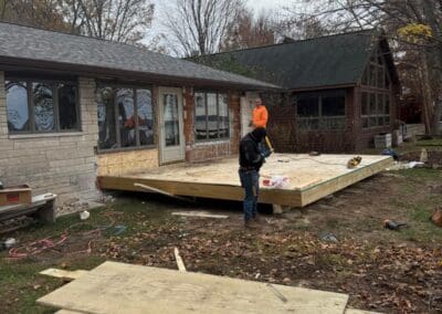 Construction workers building a spacious wooden deck attached to a house, showcasing craftsmanship in outdoor deck design and installation for functional and durable home improvements.
